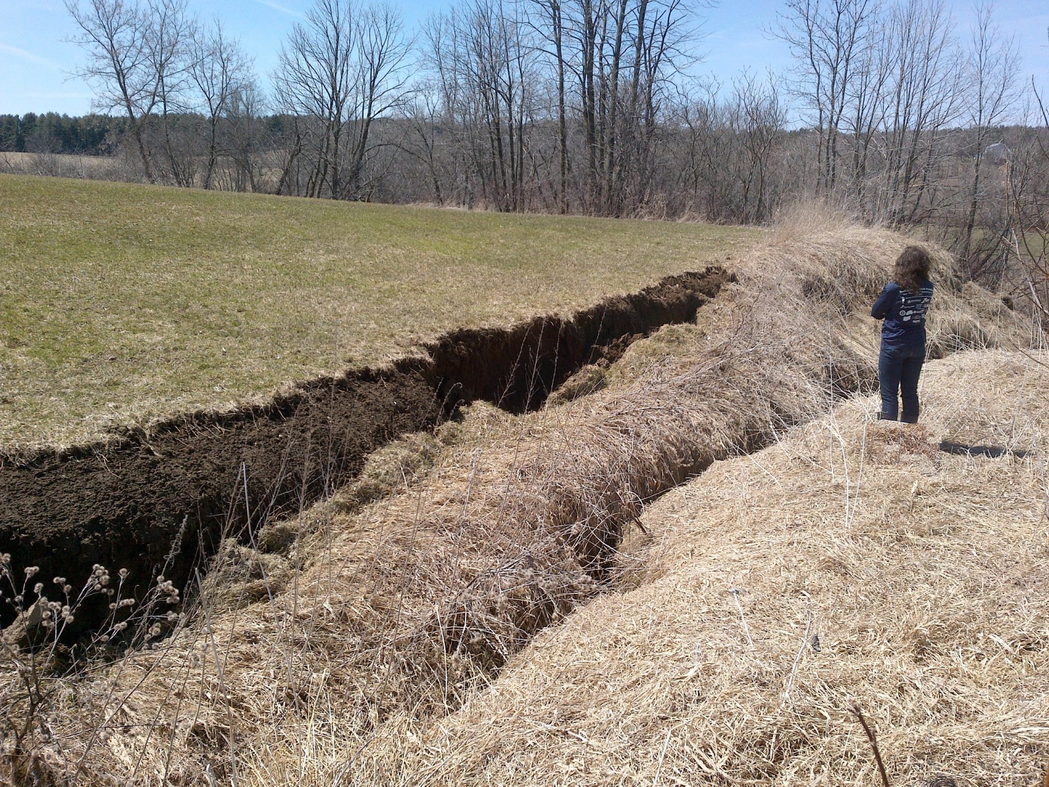 District staff stands by a small tributary to the Pike River that incised and undercut its banks, resulting in a bank failure in April 2018.