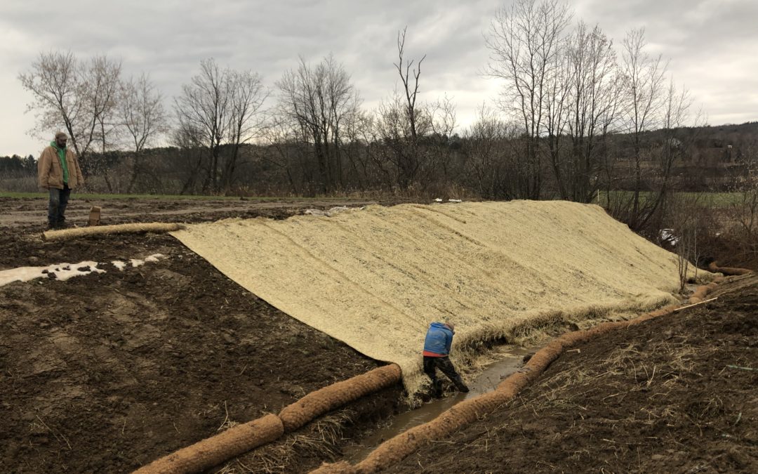 District staff, ECO-AmeriCorps members, and EcoSolutions work to install erosion control fabric on the slopes of the restored stream banks, which now lie at a more stable angle less prone to failure.
